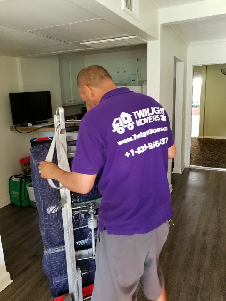 Mover team loading padded furniture into a moving truck with straps and blankets