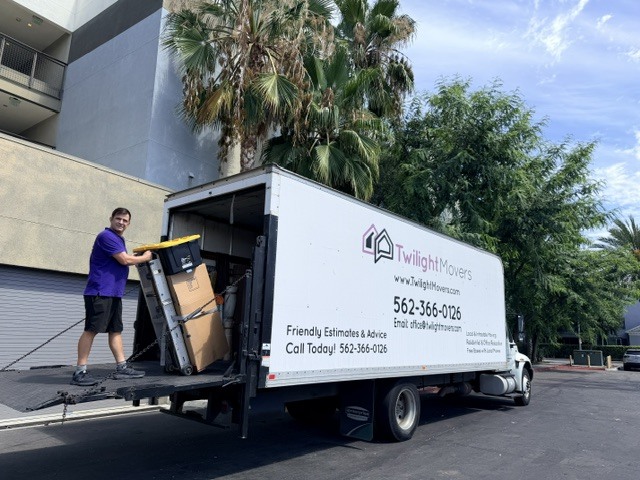 Professional movers wrapping furniture with moving blankets and stretch wrap before loading into truck