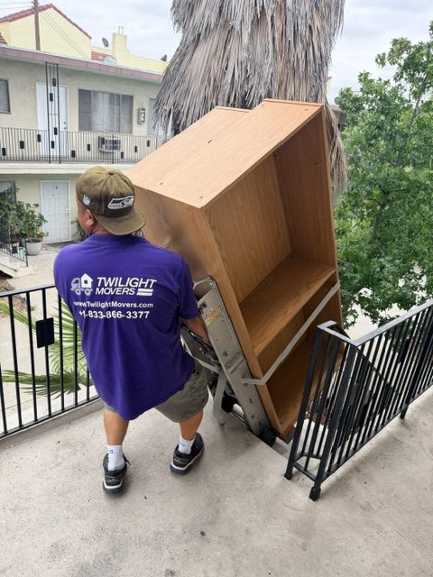 Twilight Movers professional mover safely moving large wooden furniture down apartment stairs
