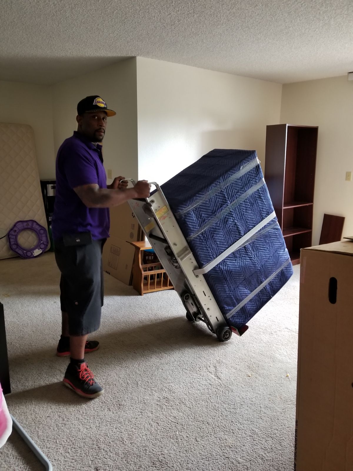 Professional mover using moving blanket and hand truck to protect furniture